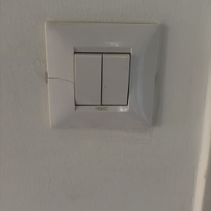 מתג חשמל על קיר לבן עם סדק קטן