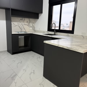 מטבח נקי עם משטחי שיש כהים וברז נירוסטה