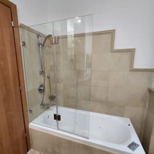 דלת זכוכית למקלחת מעל אמבטיה לבנה