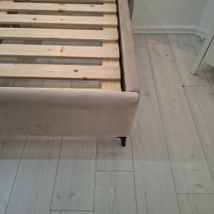 מיטה עם מסגרת עץ על רצפת עץ בהירה