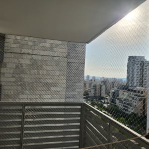 התקנת רשת שקופה נגד יונים במרפסת בבניין מגורים גבוה