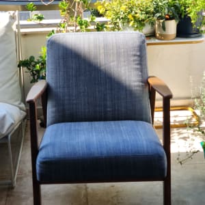 כיסא כחול על מרפסת עם צמחים מסביב