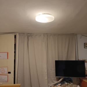 מנורה מותקנת על תקרה בחדר עם וילון וטלוויזיה