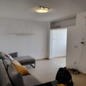 חדר עם ספה, כריות, ומזגן על הקיר