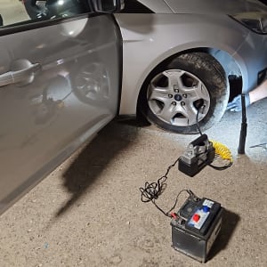 רכב עם דלת פתוחה, מצבר וכלי עבודה על הקרקע