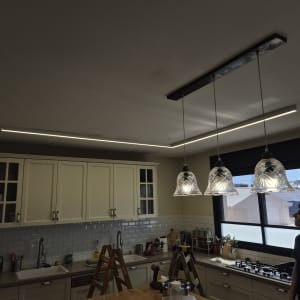 חשמלאי מתקין תאורה במטבח עם סולם וכלים