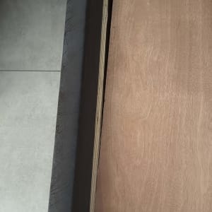 לוח עץ מונח על רצפה ליד קיר אפור