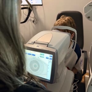 בדיקת ראייה לילד באמצעות מכשיר אופטומטרי בחדר בדיקה