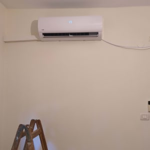 מזגן מותקן על קיר עם סולם עץ לידו