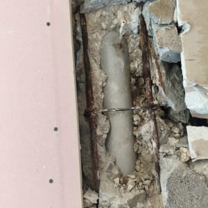 צינור חשוף בתוך קיר שבור עם ברזלים חלודים