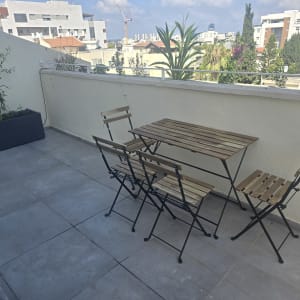 מרפסת עם שולחן וכיסאות עץ וצמחייה