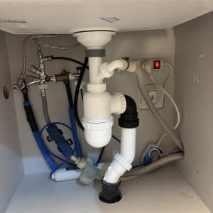 צנרת מתחת לכיור עם חיבורים וברזים