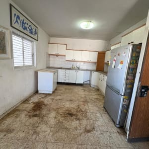 מטבח ישן עם רצפה מלוכלכת ומקרר
