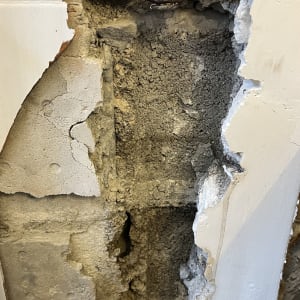 צינור חשוף בקיר עם טיח מתקלף