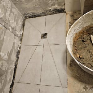 ריצוף חדש בתהליך שיפוץ עם דלי מלט