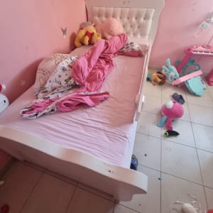 חדר ילדים עם מיטה מבולגנת וצעצועים על הרצפה