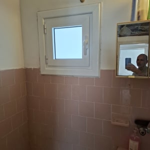 חלון אלומיניום קטן בחדר אמבטיה עם אריחים ורודים