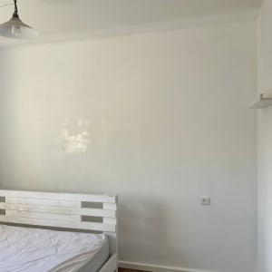 חדר עם מיטה, קיר לבן ורצפת עץ