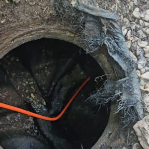 פתח ביוב עם צינור כתום ואדמה מסביב