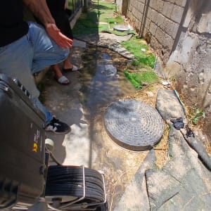 אדם בודק נזילה ליד מכסה ביוב עם ציוד מקצועי