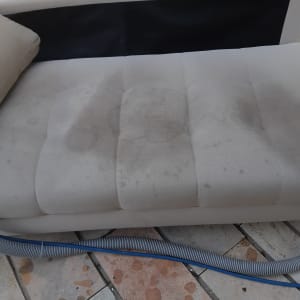 ספה מלוכלכת עם כתמים וצינור ניקוי על הרצפה