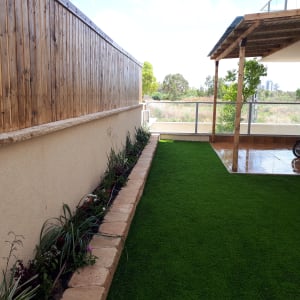 ערוגת פרחים לצד דשא סינתטי בגינה