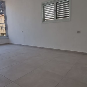 חדר ריק עם רצפת אריחים וחלון גדול