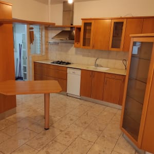 מטאטאים ודלי במטבח נקי עם ארונות עץ