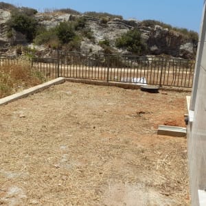 שטח אדמה יבש עם עשבים ליד גדר מתכת