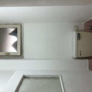 חלון קטן עם מסגרת עץ על קיר צבוע לבן