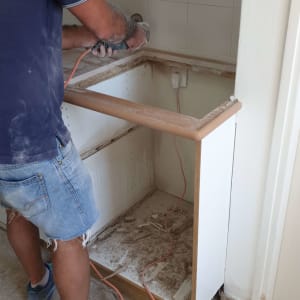 אדם עובד עם כלי חשמלי על ארון מטבח