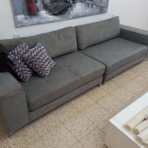 ספה אפורה עם כריות על רצפת אריחים