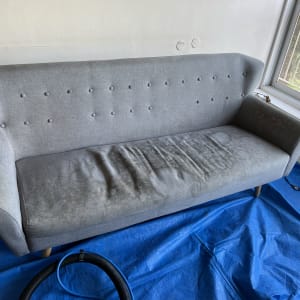 ספה אפורה עם כתמים על יריעת פלסטיק כחולה