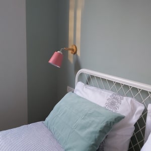 קיר צבוע בגוון ירוק עם מנורת קיר ורודה