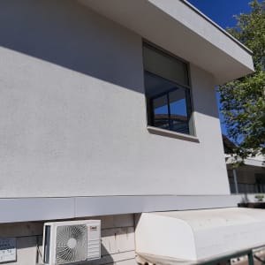 קיר חיצוני עם מזגן, חלון פתוח ועץ קרוב
