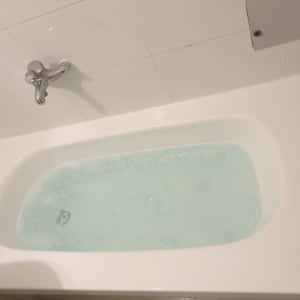 אמבטיה לבנה עם מים וברז כרום על קיר