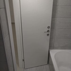 דלת לבנה חדשה עם ידית מתכת בחדר אמבטיה