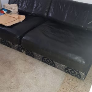 ספה שחורה עם כריות עור על שטיח בהיר