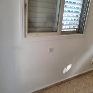 קיר לבן עם חלון פתוח וצל על הקיר