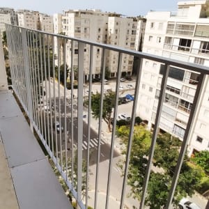 מעקה מתכת במרפסת עם נוף עירוני