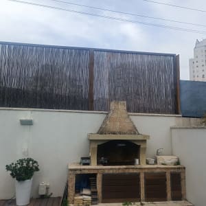 גדר עץ גבוהה מאחורי גריל אבן בגינה