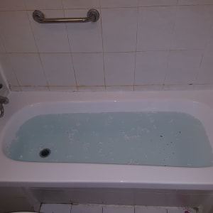 אמבטיה מלאה במים עם ידית אחיזה על הקיר