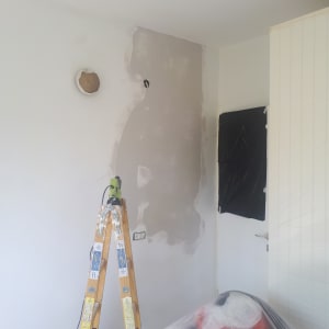 סולם עץ ליד קיר עם טיח רטוב