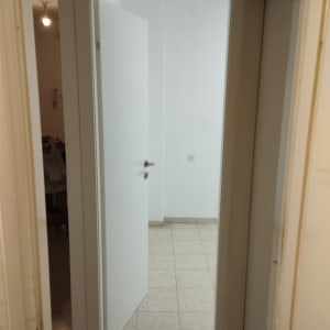 דלת לבנה פתוחה עם ידית מתכת על רצפת אריחים