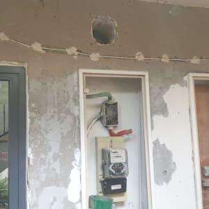 קיר עם חור, ארון חשמל פתוח, צינורות חשמל ירוקים ואדומים