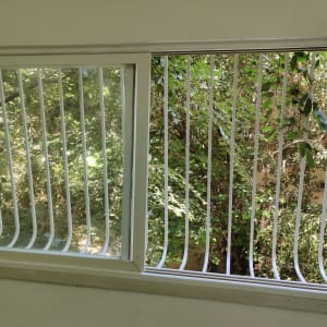 חלון עם סורגים לבנים מול עצים ירוקים