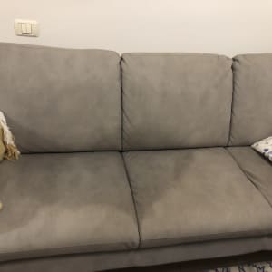 ספה אפורה עם כריות ושמיכה