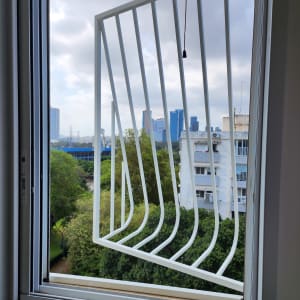 סורג מתכת לבן בחלון פתוח עם נוף עירוני