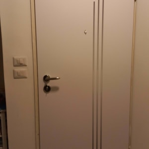 דלת לבנה עם ידית מתכת ועיטורים אנכיים