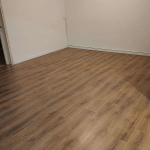 רצפת פרקט עץ בחדר ריק עם קירות לבנים